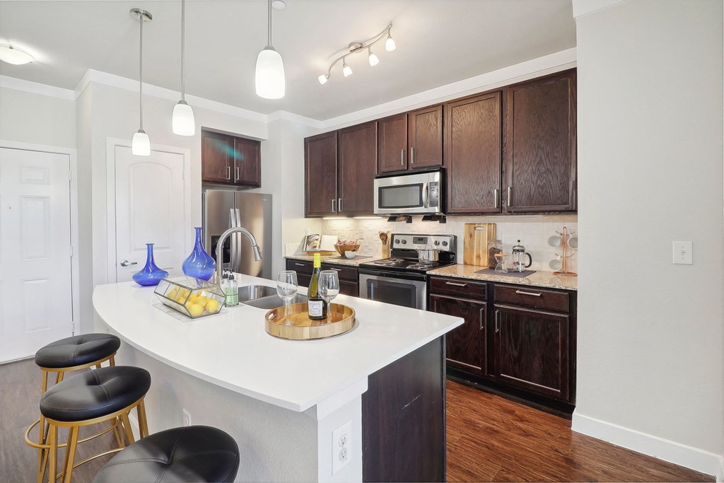 an open kitchen with a large white island and wooden cabinets