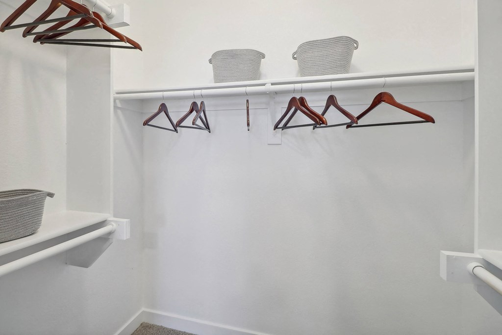 a walk in closet with hooks and a white wall