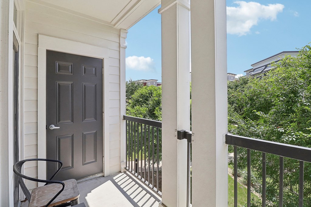 a balcony with a black door and a table and a chair