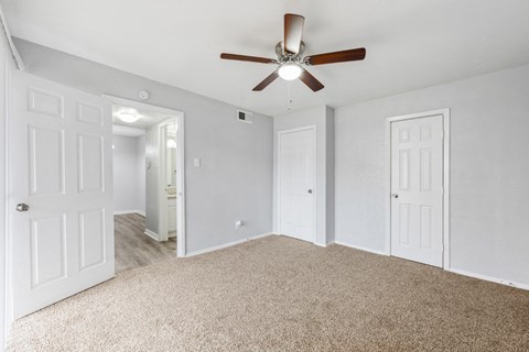 an empty bedroom with a ceiling fan and white doors