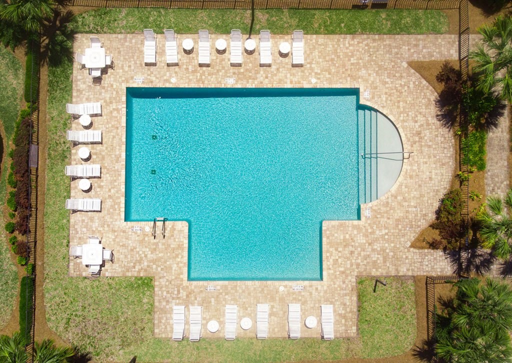 An aerial view of a swimming pool surrounded by lounge chairs and palm trees.