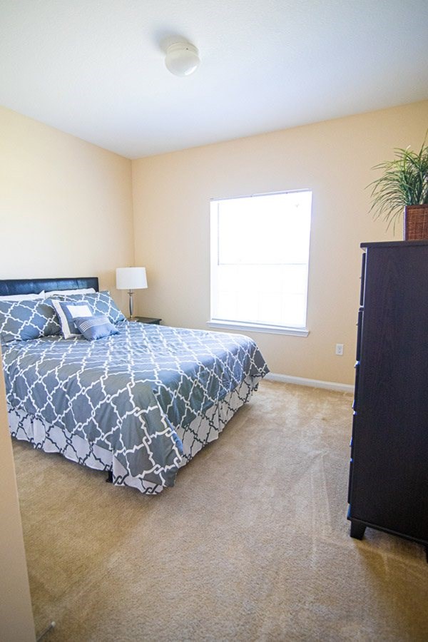 A bedroom with a bed, dresser, and window.