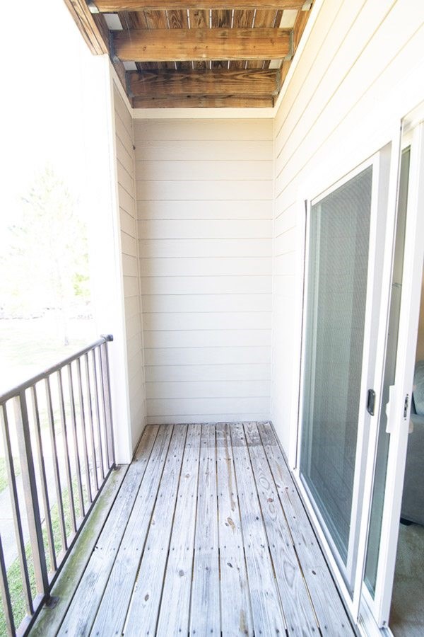 A white door is on the right side of a wooden deck.