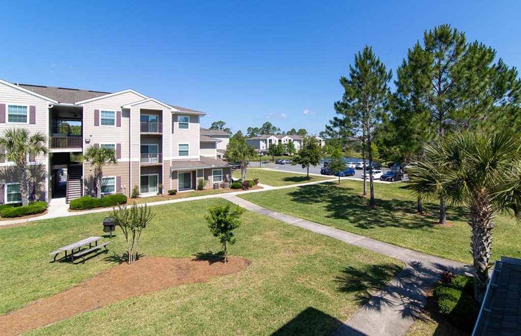 Apartment complex with a green lawn and trees.