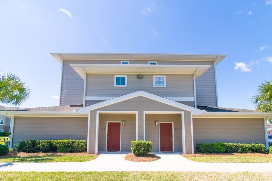 A house with a grey facade and two red doors.