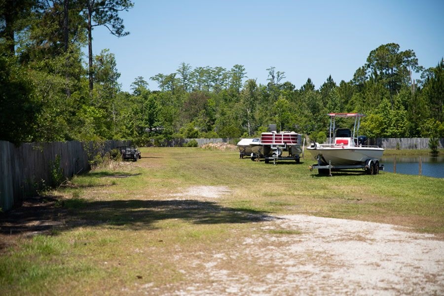 A boat is parked on a trailer in a grassy area.