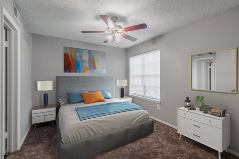 A bedroom with a bed, two nightstands, a ceiling fan, and a painting on the wall.