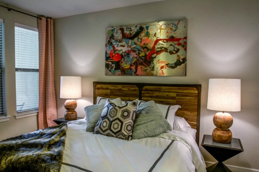 a bedroom with a bed and lamps and a painting on the wall