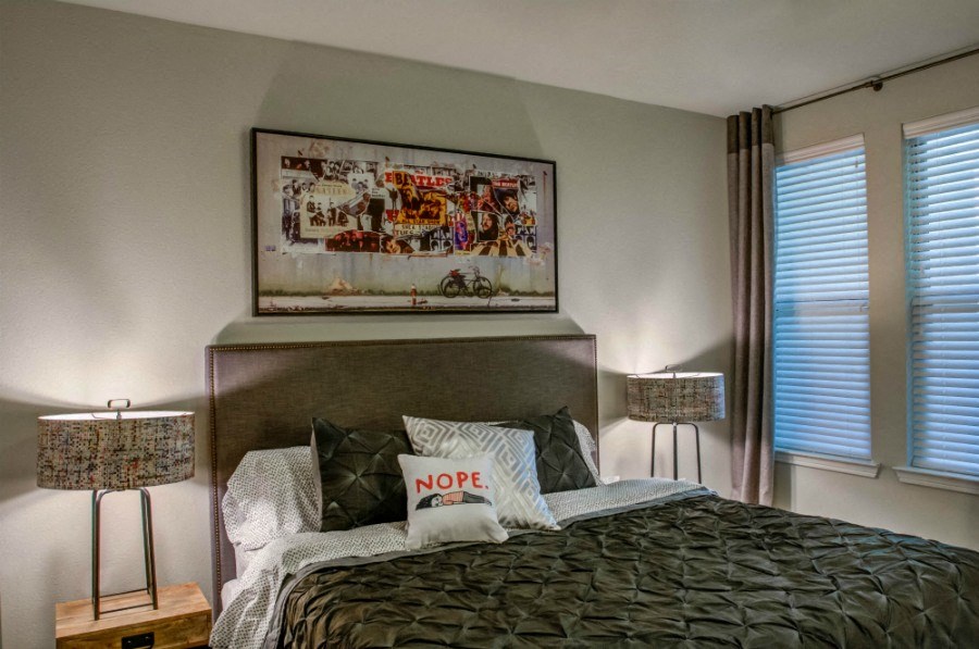 a bedroom with a bed and two lamps and a painting on the wall