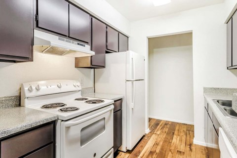 A kitchen with a white stove top oven and a white refrigerator.