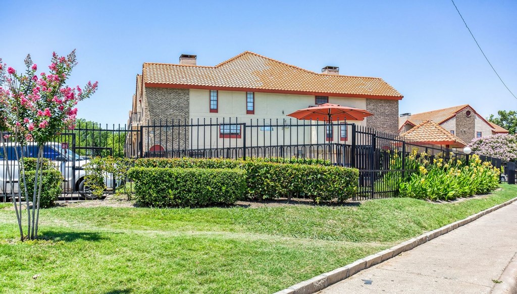 a house with a yard behind a fence and an umbrella