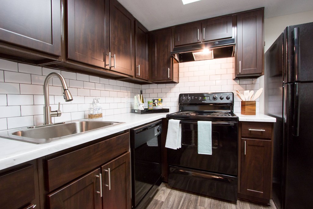A kitchen with dark wood cabinets and black appliances.