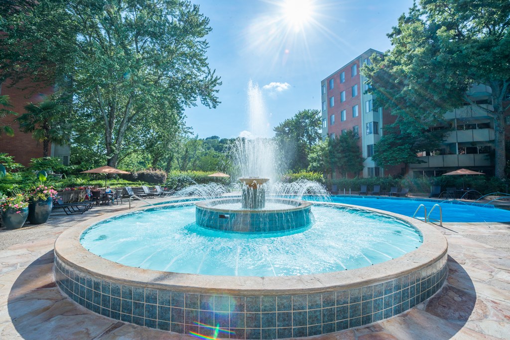 a fountain in the middle of a courtyard with a building in the background