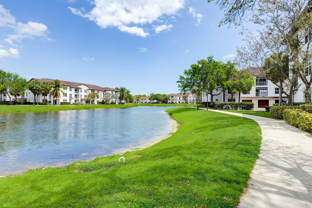 a pathway around a lake with houses on the side of it