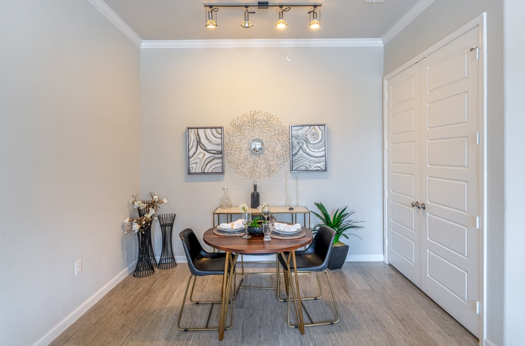 A dining room with a table set for two and a potted plant.