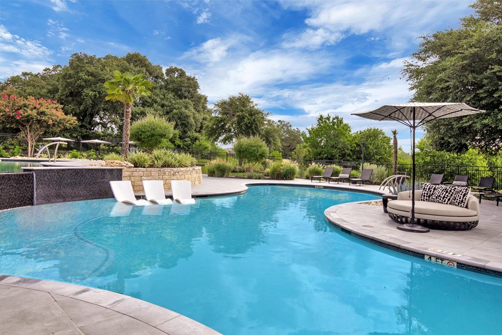 a swimming pool with chaise lounge chairs and an umbrella
