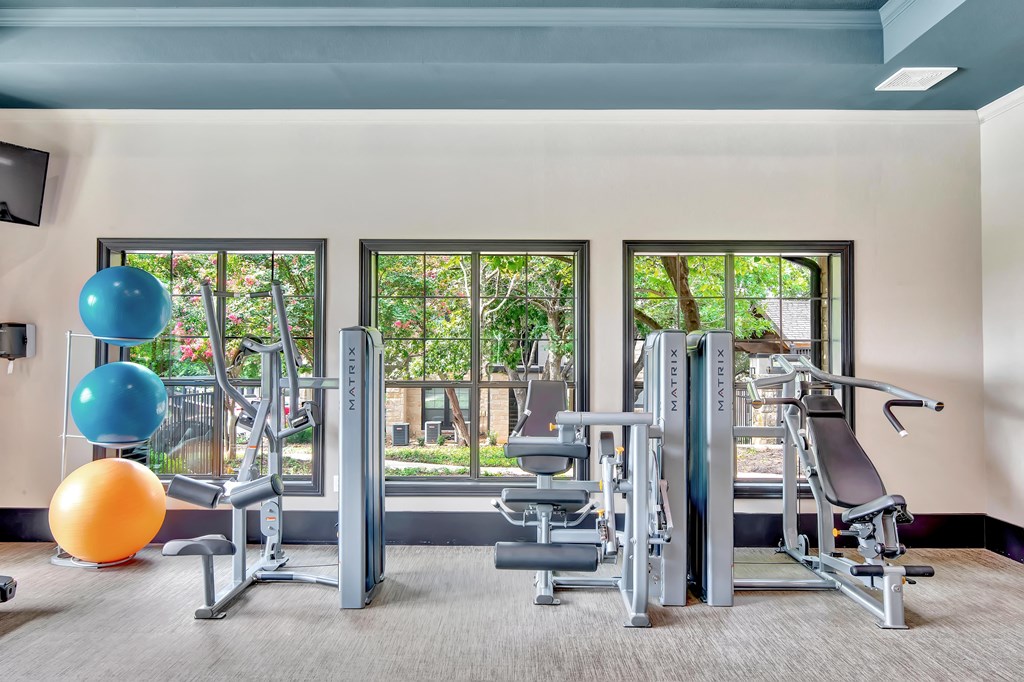 a gym with exercise equipment and large windows