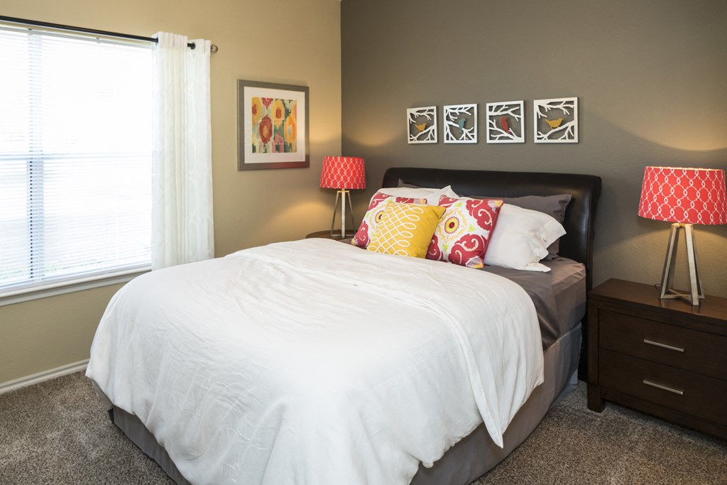 a bedroom with a large bed with a white comforter and colorful pillows