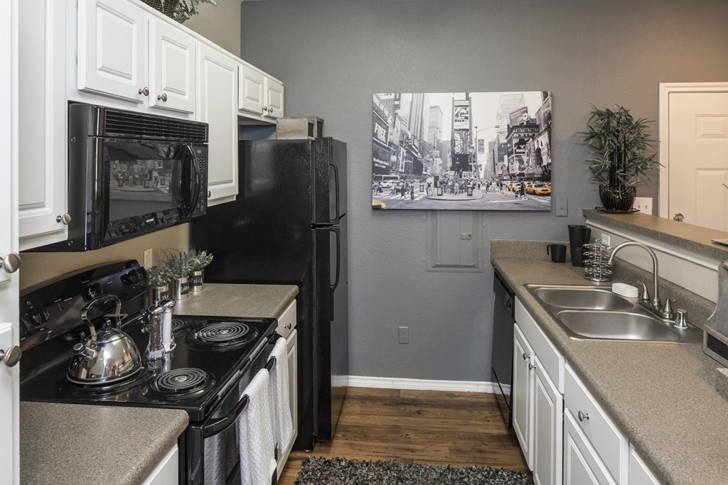 a kitchen with white cabinets and black appliances