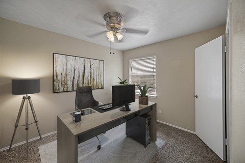 an office with a desk and a ceiling fan