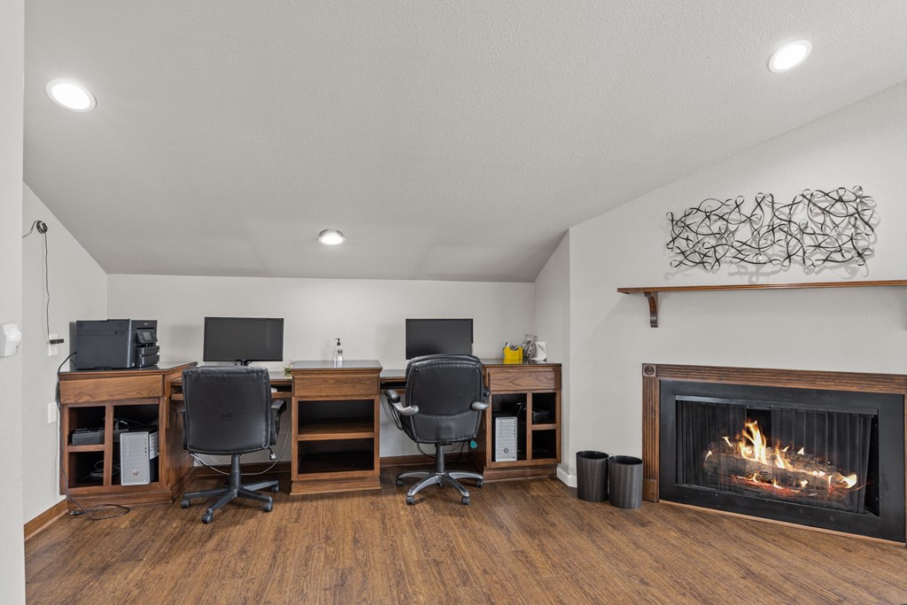 two computers and a fireplace in the corner of a room