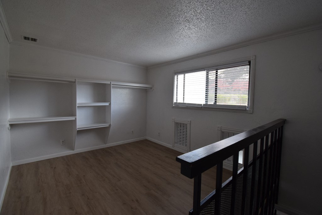 an empty living room with white shelves and a window