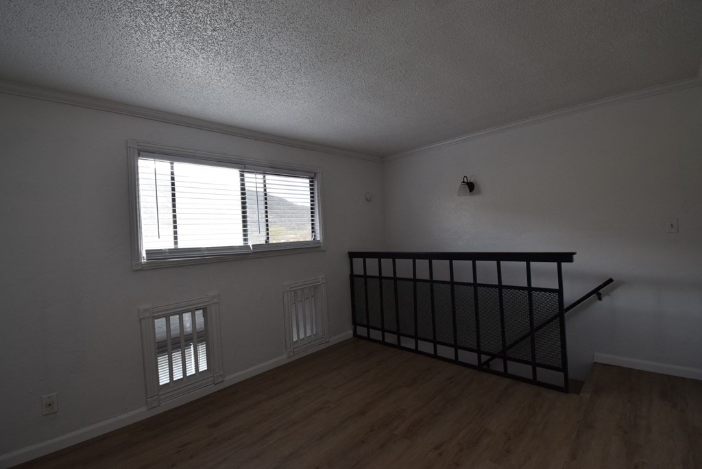 an empty living room with a staircase and a window