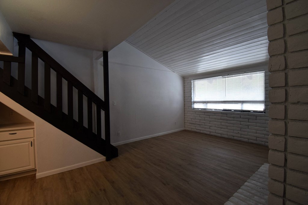 an empty living room with a staircase and a window