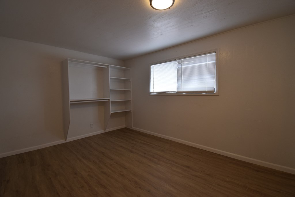 an empty living room with a window and shelves