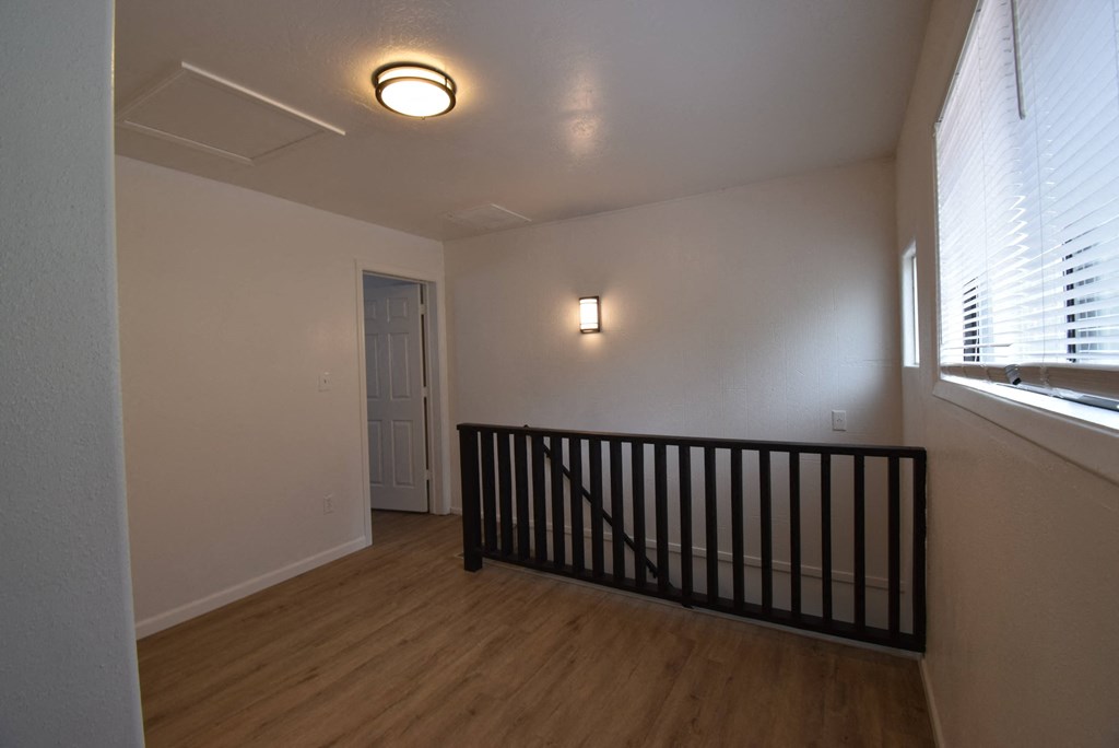 an empty living room with a railing and a window