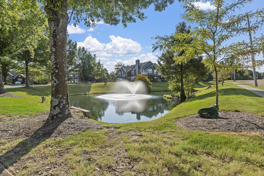 a fountain in a pond with a house in the background