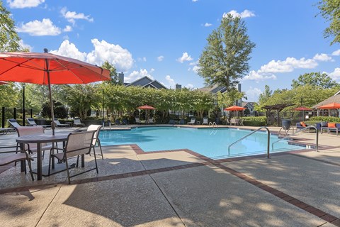 a swimming pool with tables and umbrellas next to it