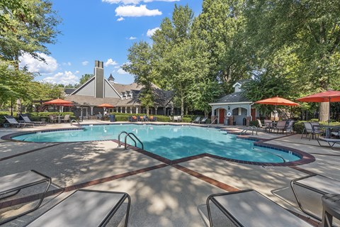 a resort style pool with chairs and umbrellas and a building in the background