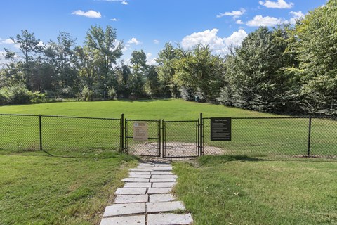 a pathway leading through a fence to a field with a sign