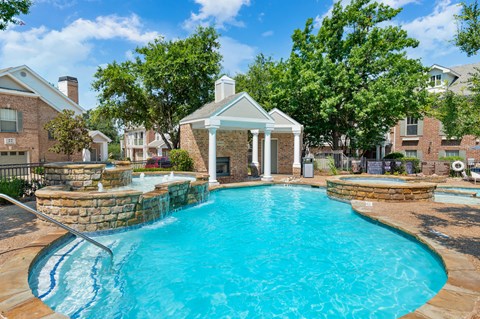 Resort-style pool with stone waterfall features, spa area, and shaded cabana.