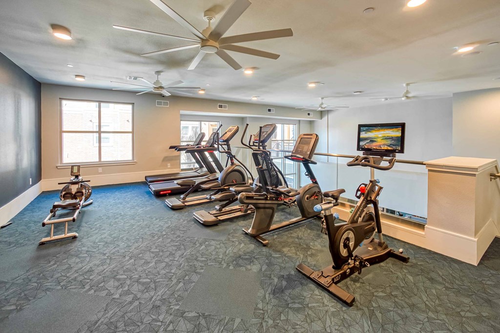 a gym with various machines and a ceiling fan