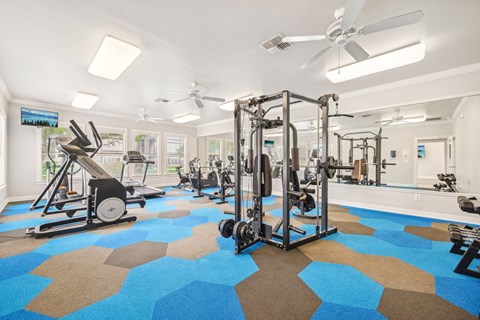 a gym with weights and cardio machines and ceiling fans