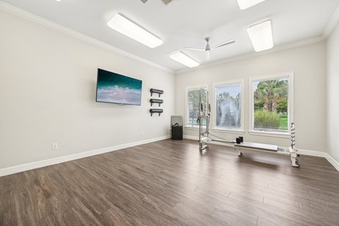 a yoga room with a reformer and three windows on the wall