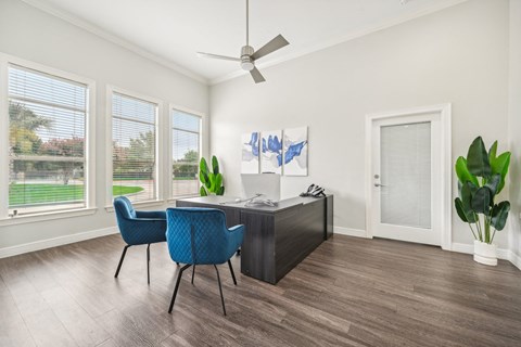 an office with a desk and chairs and a ceiling fan