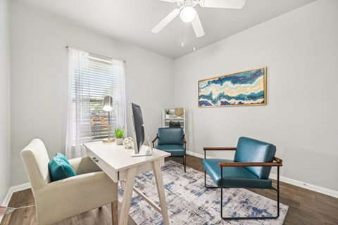 a living room with chairs and a table and a ceiling fan