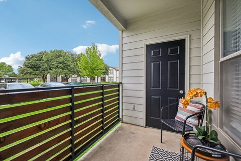 a balcony with a black door and a chair on it