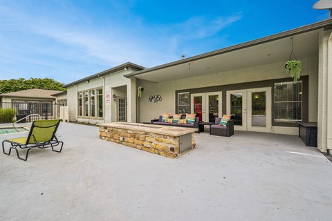 a patio with a fire pit and chairs and a house