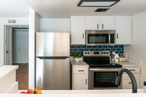 a renovated kitchen with stainless steel appliances and white cabinets