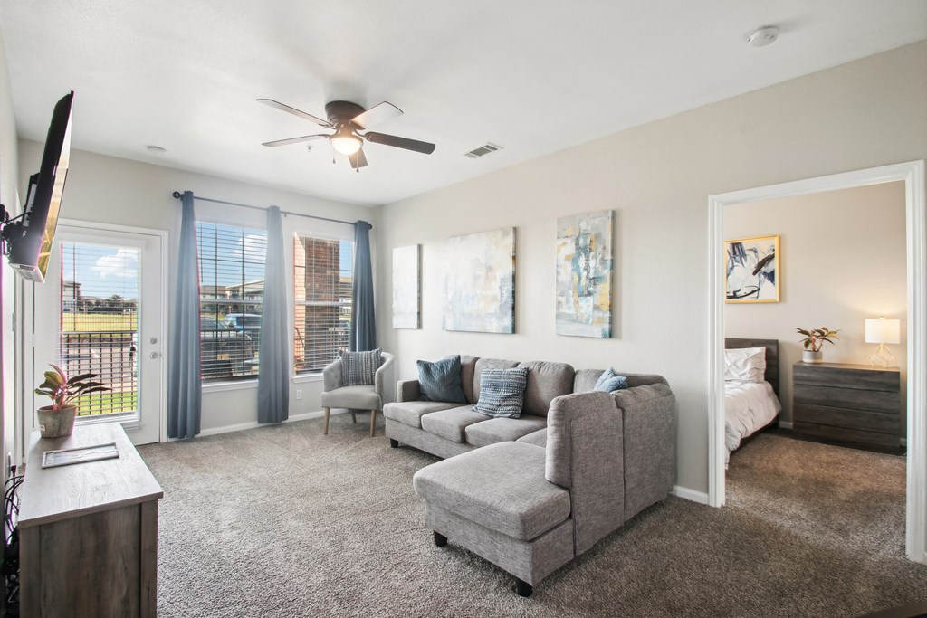a living room with a couch and a chair and a ceiling fan