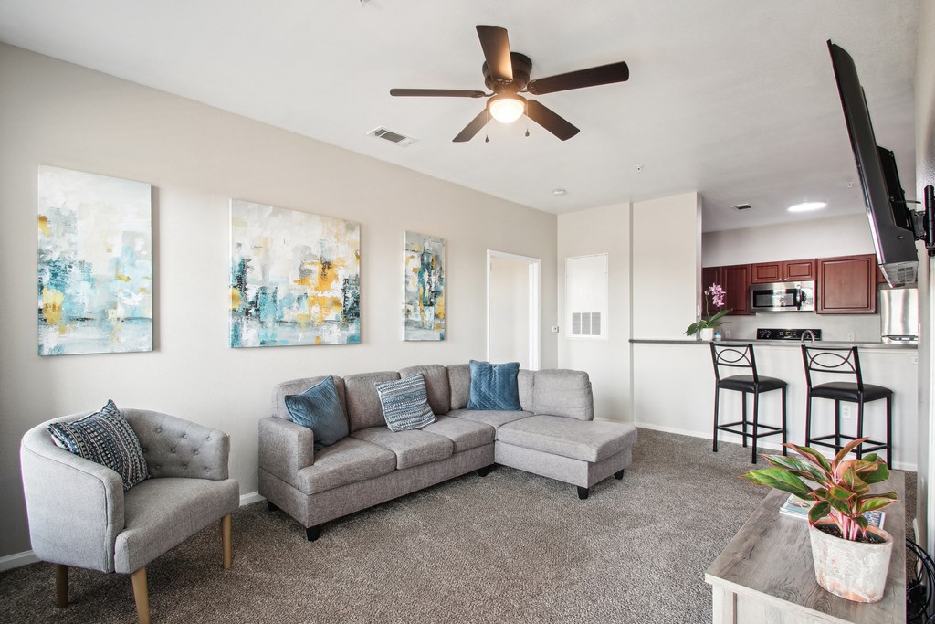 a living room with a couch and a chair and a ceiling fan
