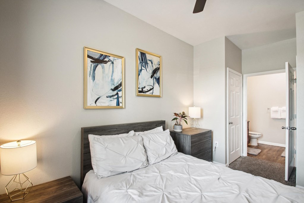 a bedroom with a white bed and two paintings on the wall