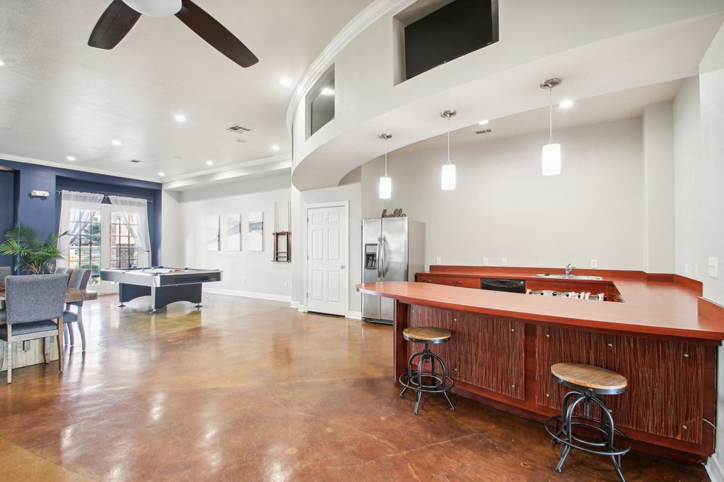 a game room with a pool table and a bar with stools