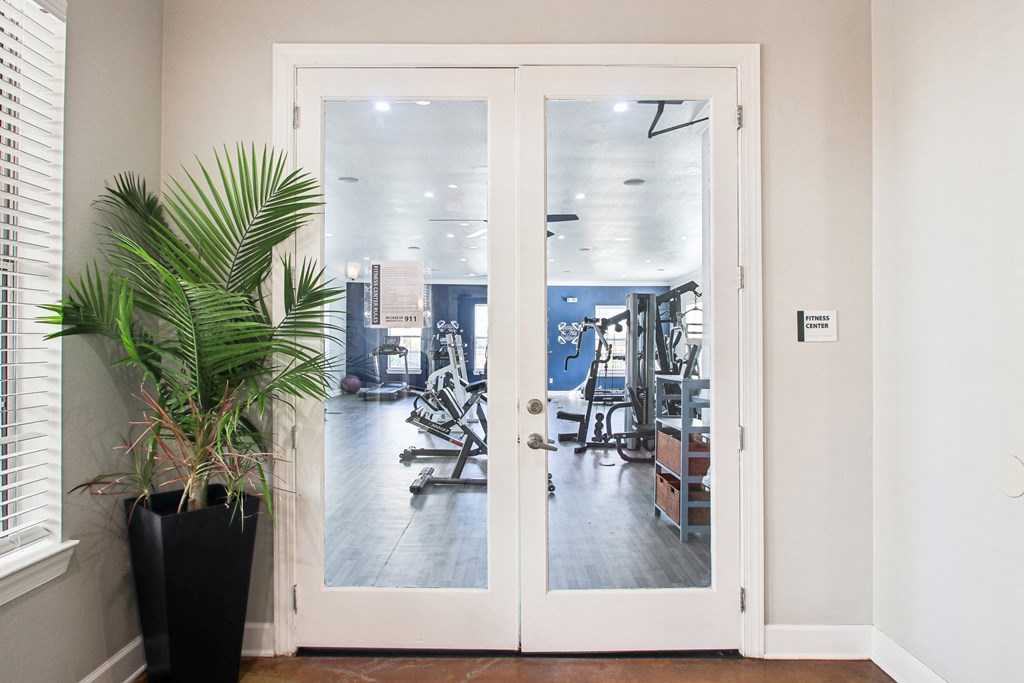 a door to a gym with a plant and exercise equipment