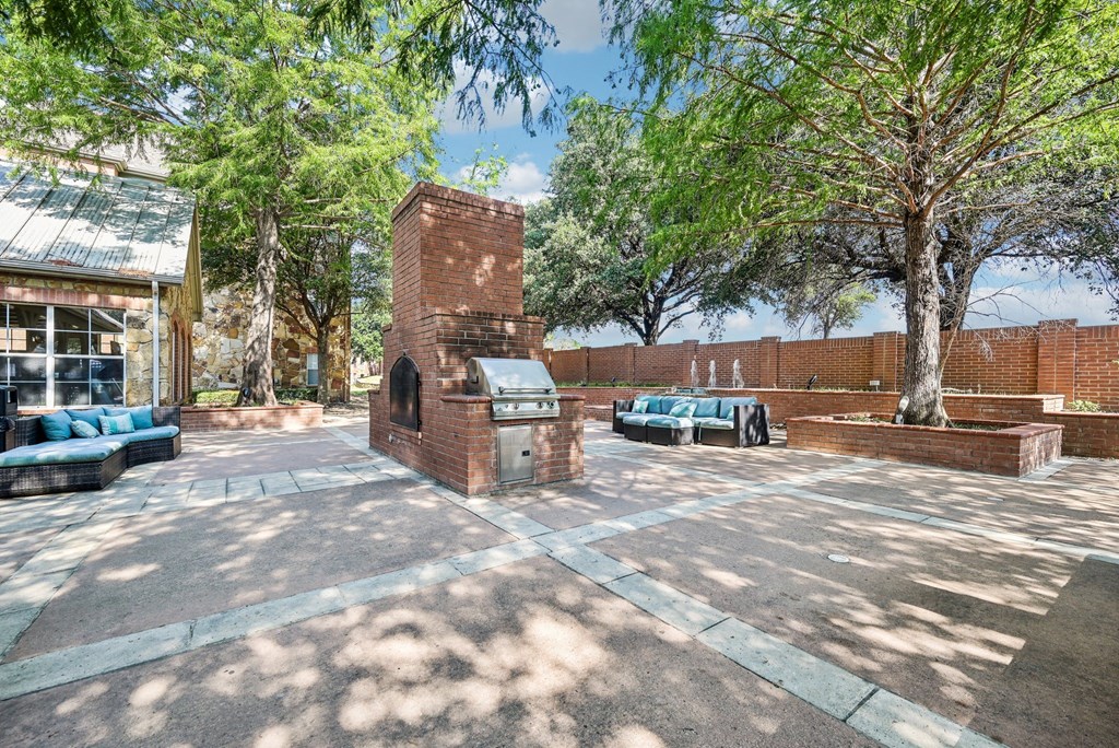 a courtyard with trees and a brick building with a grill