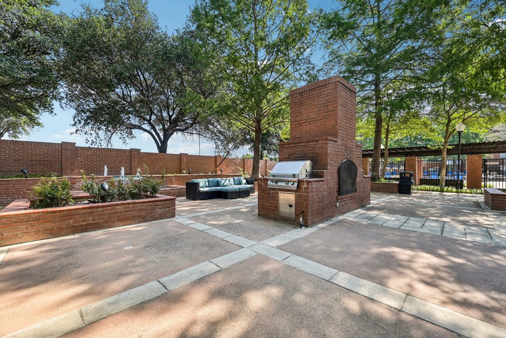 a brick fireplace in the middle of a courtyard with trees